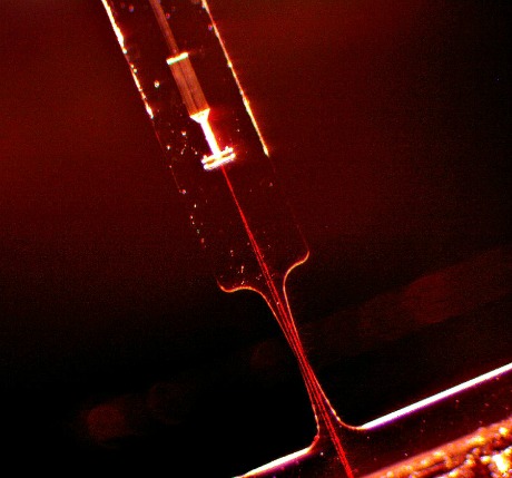 Top view of a fused silica notch flexure with a Mach-Zehnder located at the substrate mid-plane. In this photograph red light is coupled into the system to make the various waveguide segments visible